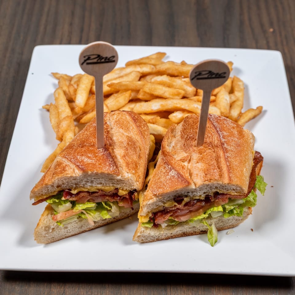 Pino Wine Bar & Bistro's sandwich cut in half with fries on a white plate.
