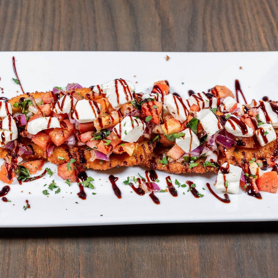 Crispy chicken cutlet topped with diced tomatoes, red onions, mozzarella, and balsamic glaze.